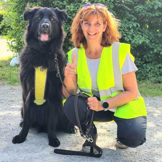 Die Trainerin Tanja von Nasensache - Mantrailing Pur aus Köln hockt neben ihren schwarzen Hund